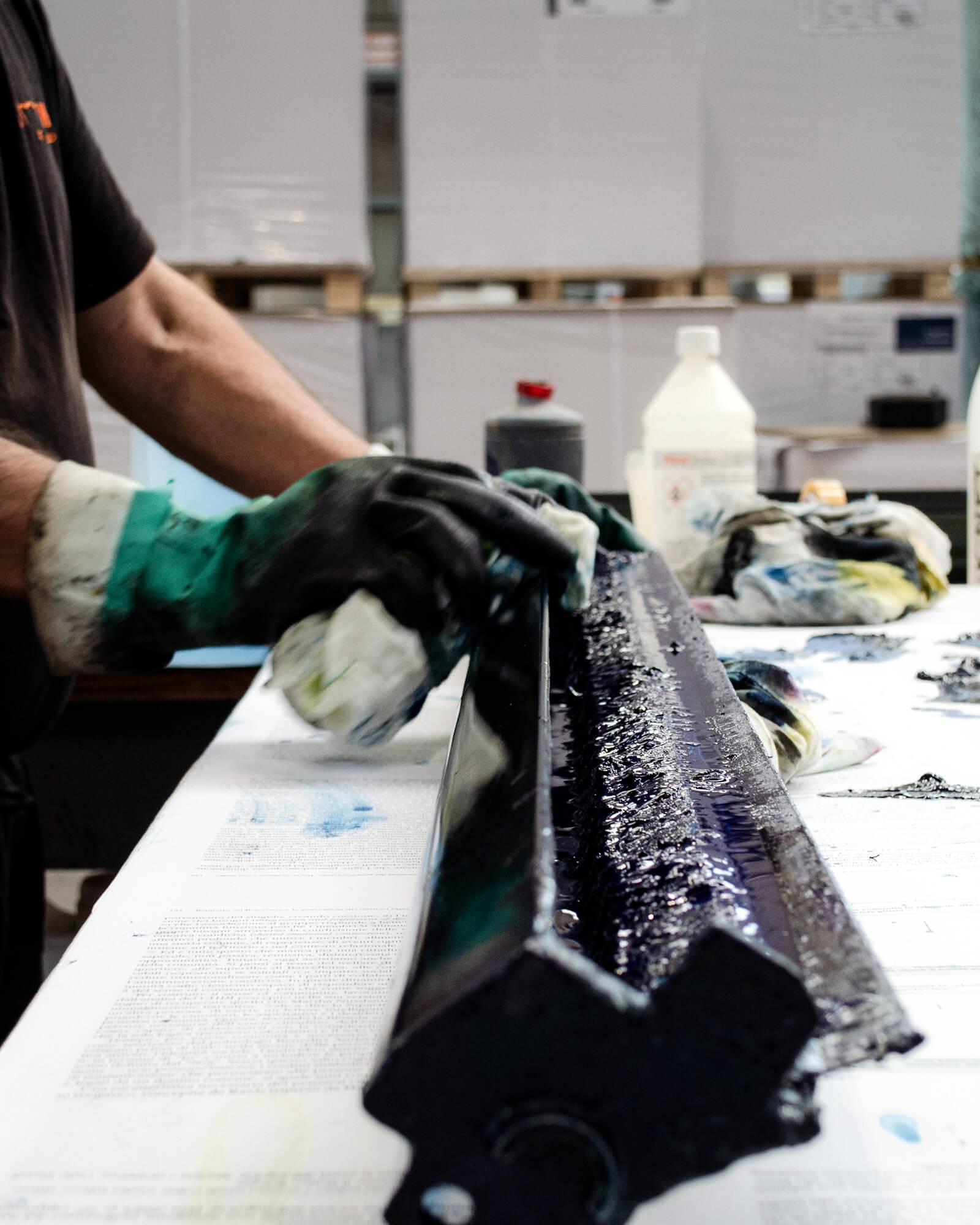 Mani con i guanti che lavorano il rullo dell'inchiostro di una macchina offset