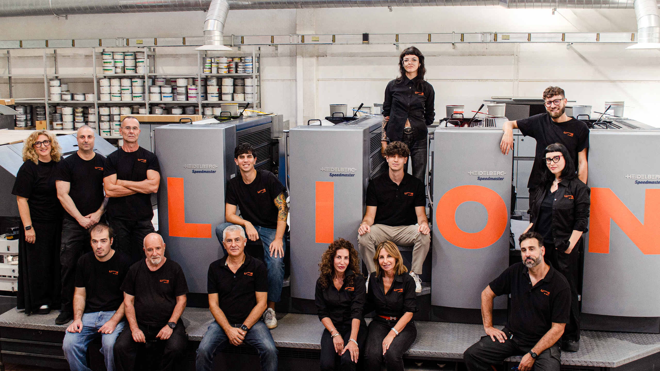 Il team di Lion Brand davanti alla macchina offset con le lettere LION