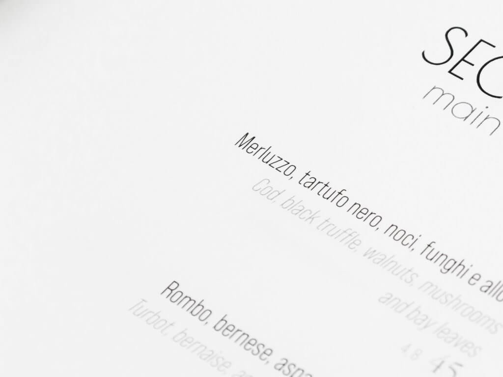 La pagina «Secondi / main courses», di taglio, con i piatti in italiano e inglese e i prezzi, Pulejo, Lion Brand