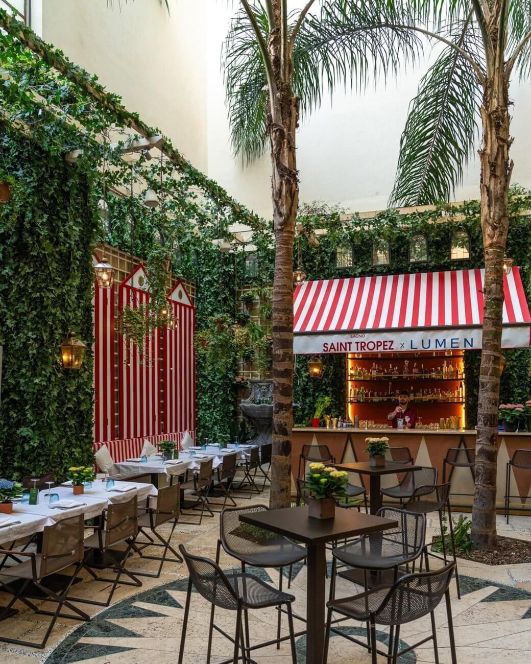 La corte del St. Regis con pannelli a strisce bianche e rosse, cabine e bar, Lumen Garden, Lion Brand