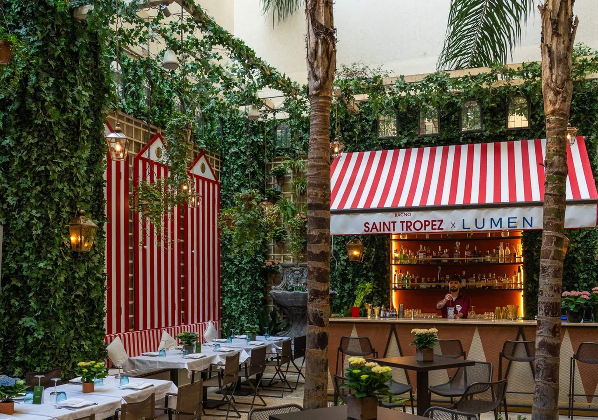 La corte del St. Regis con pannelli a strisce bianche e rosse, cabine e bar, Lumen Garden, Lion Brand