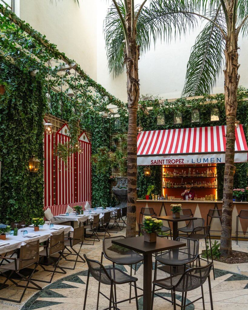 La corte del St. Regis con pannelli a strisce bianche e rosse, cabine e bar, Lumen Garden, Lion Brand