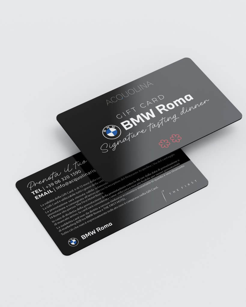 La gift card nera, fronte e retro, con i loghi BMW e The First e i contatti di Acquolina, The First e BMW Roma, Lion Brand