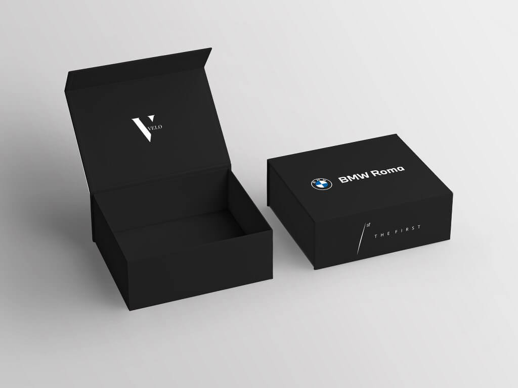 La scatola nera aperta col logo The First nel coperchio e la scatola chiusa «BMW Roma / The First», The First e BMW Roma, Lion Brand