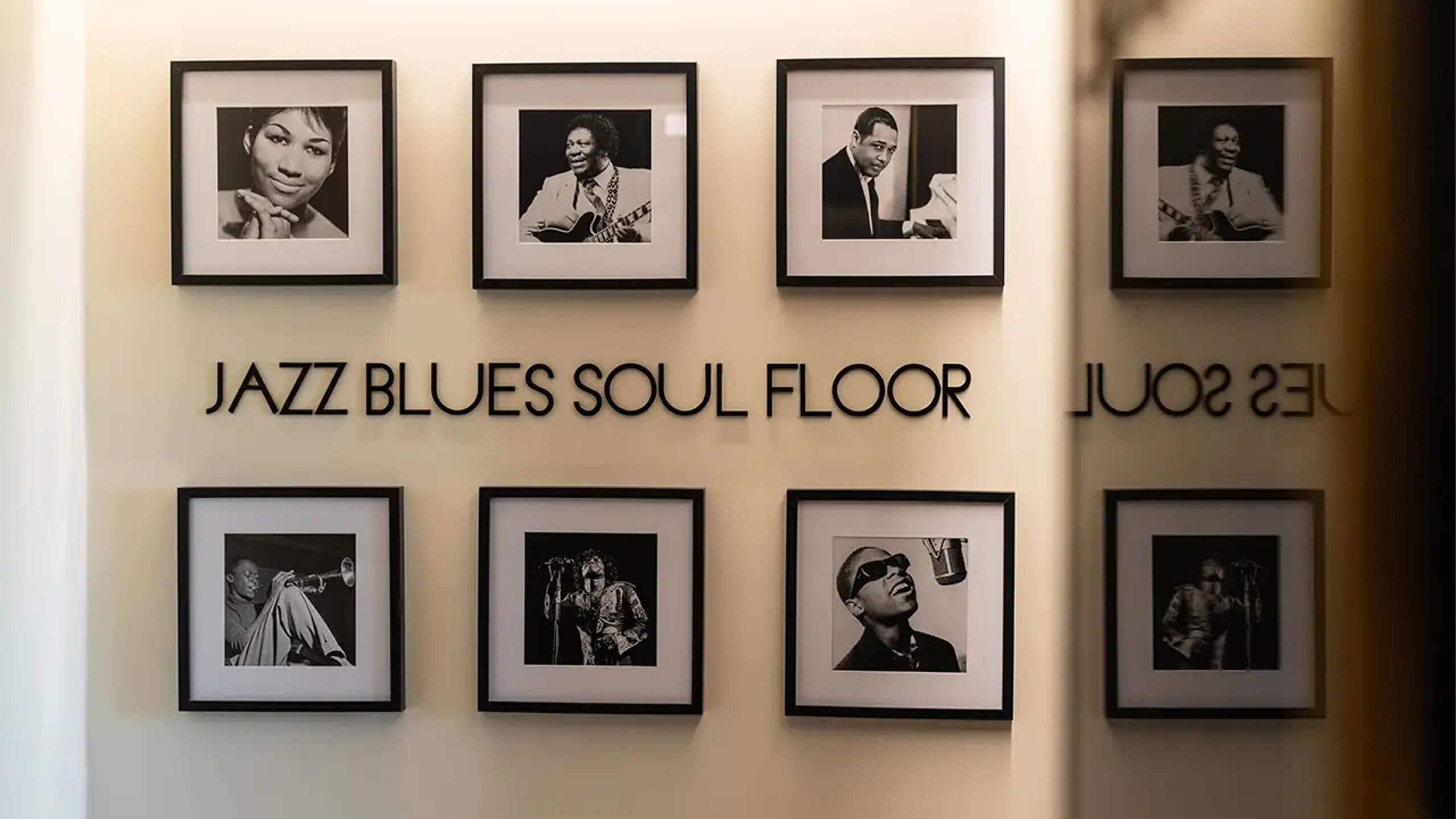 La parete «JAZZ BLUES SOUL FLOOR»: lettere in rilievo e due file di ritratti in bianco e nero incorniciati, The First Musica, Lion Brand