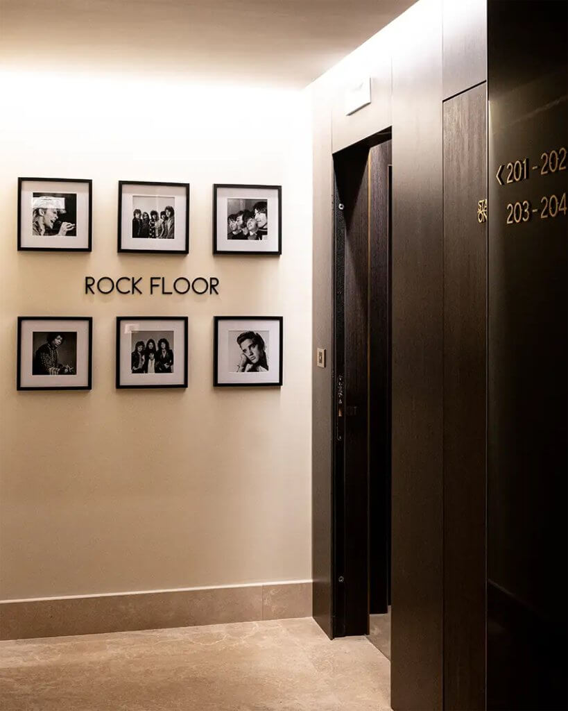 Il corridoio «ROCK FLOOR»: la scritta, sei ritratti incorniciati, la porta dell'ascensore e i numeri delle camere 201-204, The First Musica, Lion Brand