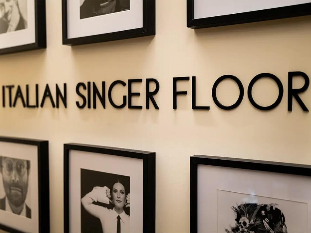 La parete «ITALIAN SINGER FLOOR» con le lettere e i ritratti incorniciati, The First Musica, Lion Brand