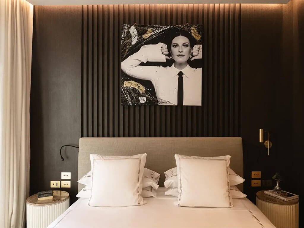 Una camera: un ritratto a colori sopra il letto, doghe scure, lampade, The First Musica, Lion Brand