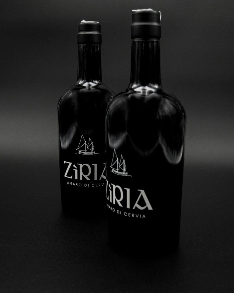 Due bottiglie affiancate su fondo nero, riflessi sul vetro, marchio bianco, Zìria, Lion Brand